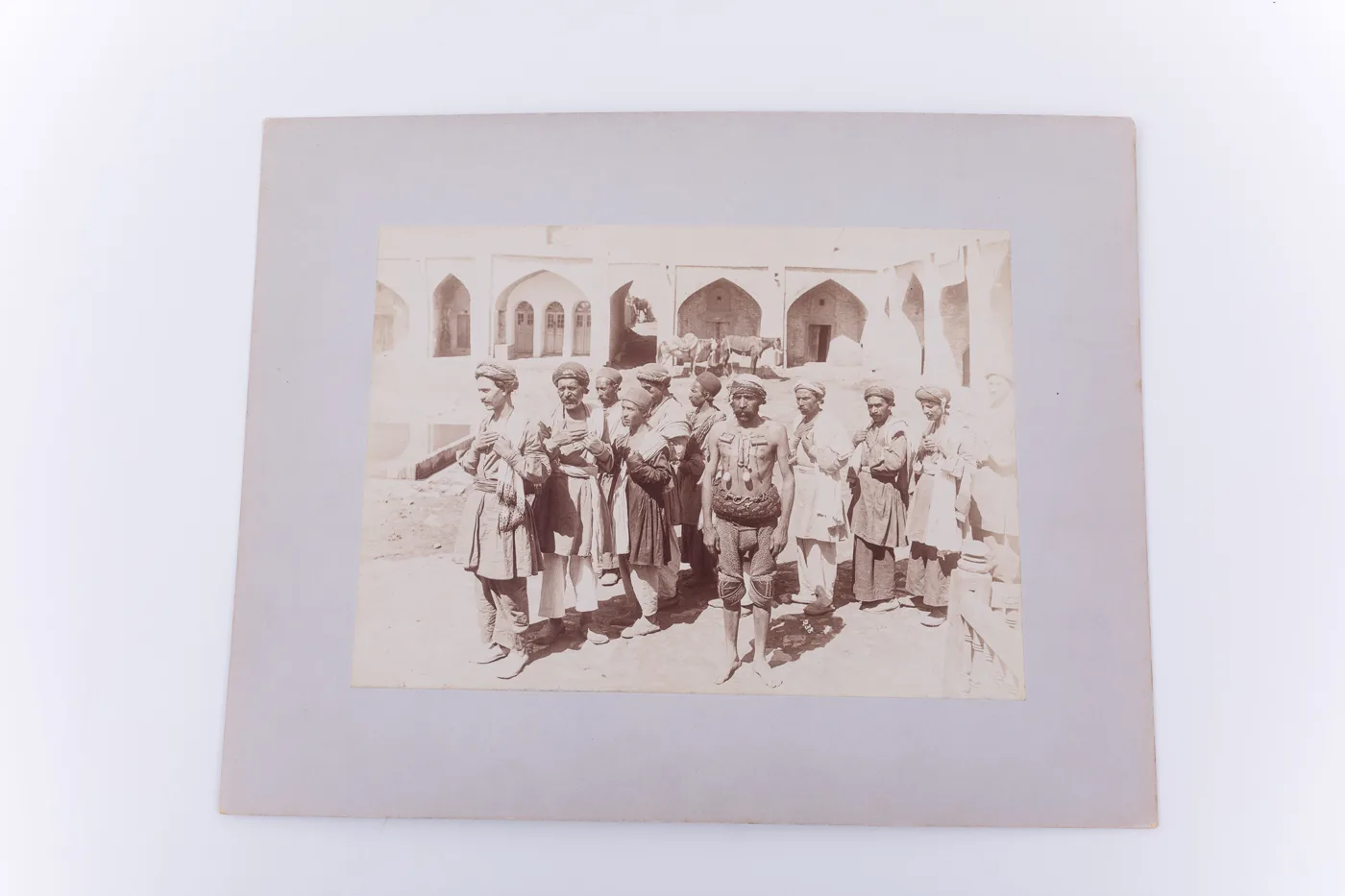 Fotografie de exterior ce prezintă un grup de bărbați. Poziția corpului și a mâinilor acestora indica faptul că se află la o ceremonie. În centrul lor se află un bărbat în costum de luptător, ce are p — تصویر رکورد یوروپیانا