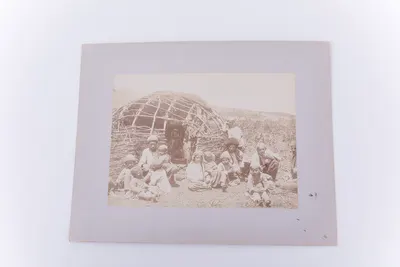 Fotografie de exterior ce prezintă un grup de nomazi, cel mai probabil o familie cu nouă copii. Se remarcă în în plan secund o locuință provizorie realizată din nuiele, parțial acoperită cu o prelată. — تصویر رکورد یوروپیانا