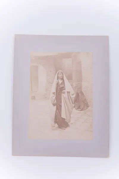 Fotografie de exterior ce prezintă o femeie în costum persan, pe o stradă. Se remarcă, în plan secund, o altă femeie, în poziție ghemuită. Imaginea este realizată pe hârtie albuminată, după un clișeu  — تصویر رکورد یوروپیانا
