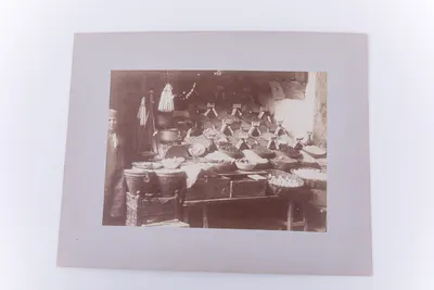 Fotografie de exterior ce prezintă o femeie în port, lângă un stand cu mirodenii. Imaginea este realizată pe hârtie albuminată, după un clișeu pe sticlă și este lipită pe un carton gros, de culoare gr — تصویر رکورد یوروپیانا