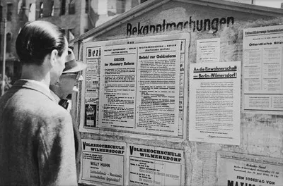 Währungsreform in den westlichen Sektoren im Juni 1948. Einwohner vor Plakatwand mit zweisprachiger Bekanntmachung der britischen Militärregierung — تصویر رکورد یوروپیانا