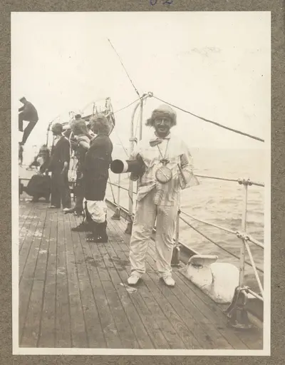 Bilden föreställer antagligen navigatorn i Neptuns hovstat under linjedopet ombord på Fylgia. Han är utrustat med en stor klocka och en sextant i trä. Hans uppgift är att kungöra tidpunkt och position — تصویر رکورد یوروپیانا