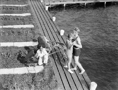 Model Eva Waldschmidt en model Grummels dansen aan de oever van de Westeinderplassen, links bij de koffergrammofoon een onbekende vrouw — تصویر رکورد یوروپیانا