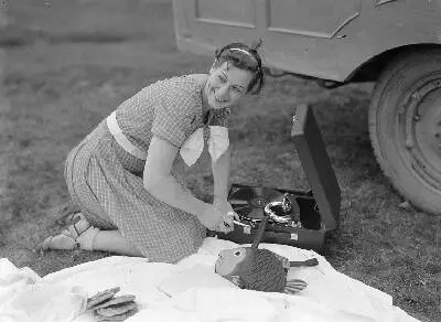 Zeven vriendinnen maken een uitstapje. Daisy, een van de dames, maakt de koffergrammofoon speelklaar — تصویر رکورد یوروپیانا
