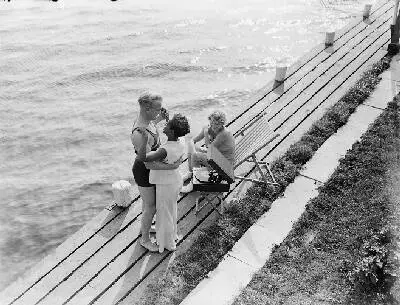 Model Grummels (l), een onbekende vrouw en model Eva Waldschmidt (zittend) bij de Westeinderplassen, tussen hen in een koffergrammofoon — تصویر رکورد یوروپیانا