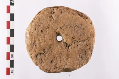 Greutate aproximativ circulară, de dimesiuni medii spre mari, realizată prin refolosirea unei cărămizi. Piesa este prevăzută cu un orificiu cilindric de mici dimensiuni, situat în mijloc. Angobă de cu — تصویر رکورد یوروپیانا