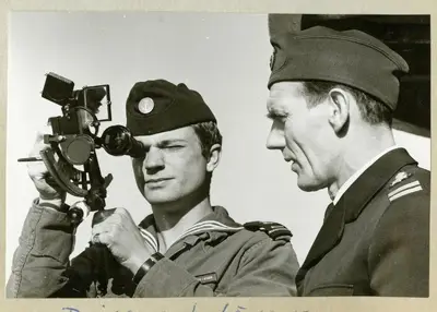 Bilden föreställer Carl XVI Gustaf och Oskar Linde under minfartyget Älvsnabbens långresa 1966-1967. På bilden använder Carl XVI Gustaf en sextant medan Oskar Linde står bredvid, båda iklädda uniform. — تصویر رکورد یوروپیانا